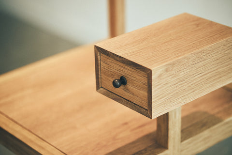 Wooden drawer with a black handle on a wooden chair's arm