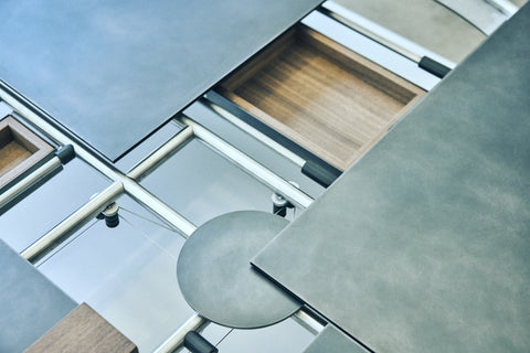 Close-up of a table with four individual parts connected by metal tubes and a wooden drawer